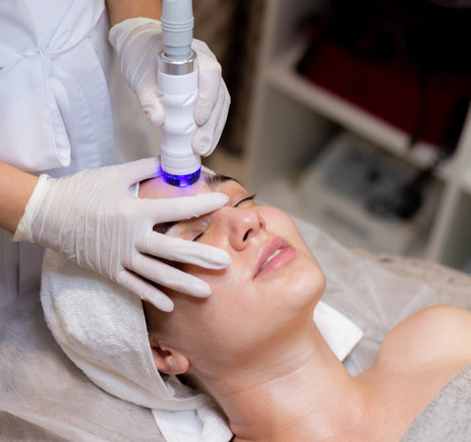 A professional performing a non-invasive cosmetic procedure, such as microneedling or dermaplaning, on a patient in a clinical setting.